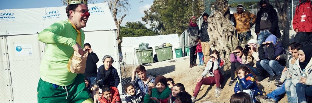 Clown i gröna kläder och krona uppträder för en grupp barn