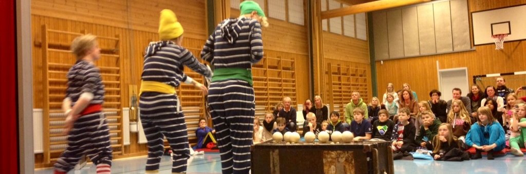 Tre clowner i randiga kläder uppträder i gymnastiksal