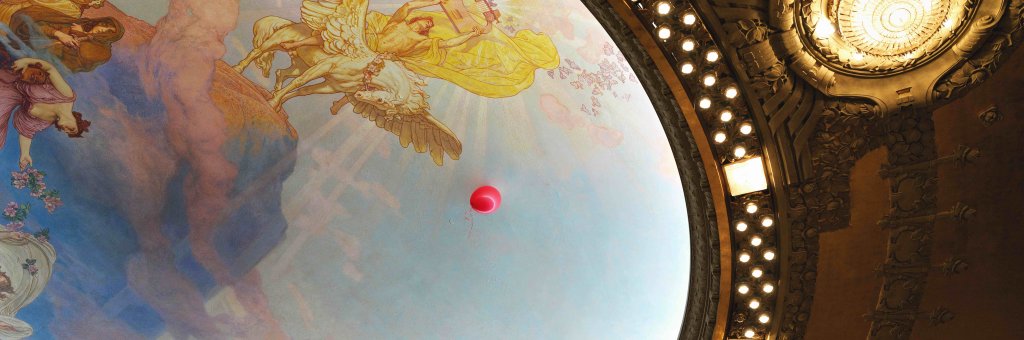 En röd ballong som svävar i Dramatens tak