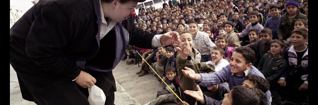 Nalle i clownnäsa och höghatt tillsammans med en skrattande publik