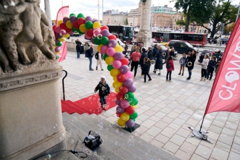 Röd matta på marken, en ballongbåge i många färger, människor som står utanför Dramatens byggnad