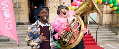 Nalle med trumbon och stor rosa krage tillsammans med en ungdom