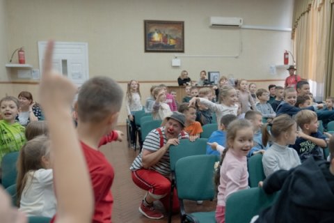 En clown gömmer sig i publiken och barnen pekar på honom