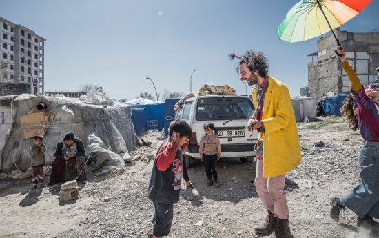 En artist med ett färgglatt paraply, en artist som spelar musik, ett barn som dansar