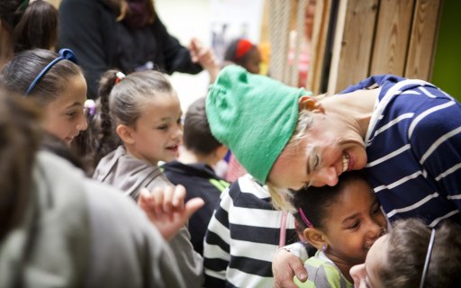 Leende clown omfamnar en flicka i publiken