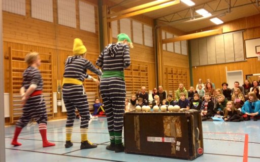 Tre clowner i randiga kläder uppträder i gymnastiksal